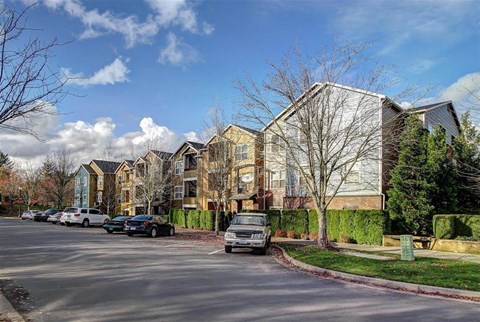 A row of houses with cars parked in front.