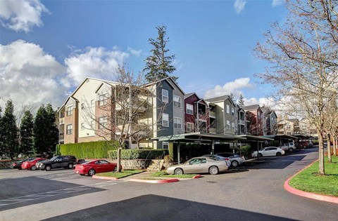 A row of townhouses with cars parked in front.