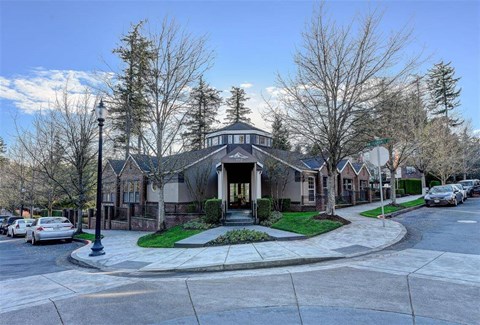 A house with a grey roof and a white fence is surrounded by trees.