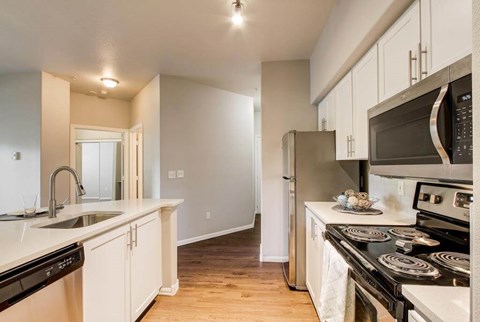 A kitchen with white cabinets and black appliances.
