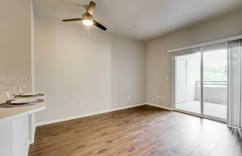 A room with a ceiling fan and sliding glass doors.