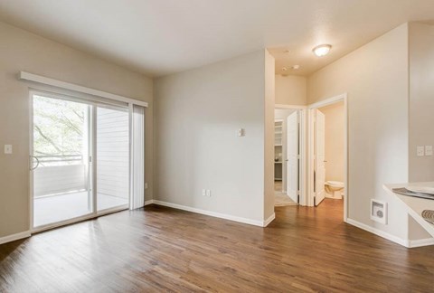 A room with a sliding glass door and wooden floors.