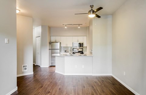 A kitchen with white cabinets and a wooden floor.