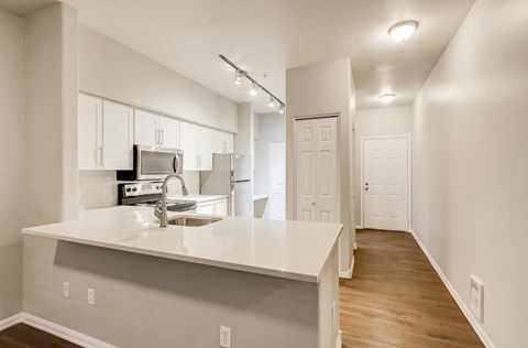 A kitchen with white countertops and wooden floors.