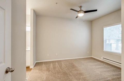 A room with a ceiling fan and carpeted floor.