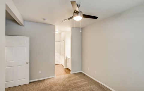 A room with a ceiling fan and carpeted floor.