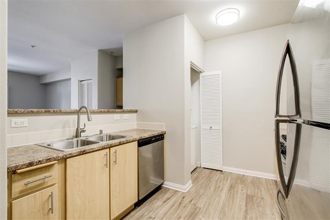 A kitchen with wooden cabinets and a surfboard leaning against the wall.