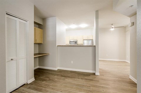 A room with a white door and a counter with a microwave and oven.