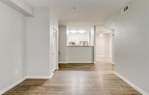 A long, empty hallway with wooden floors and white walls.