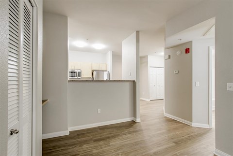 A kitchen area with a white counter and wooden flooring.