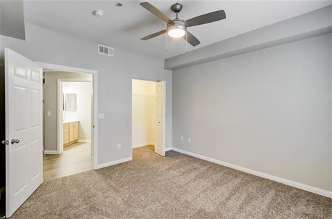 A room with a ceiling fan and carpeted floor.