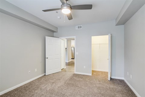 A room with a ceiling fan and carpeted floor.
