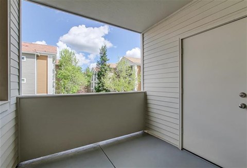 A balcony with a white door and a view of a residential area.