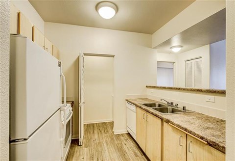 A kitchen with a refrigerator, sink, and cabinets.