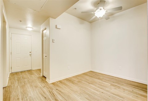 A room with a white door and a white ceiling fan.