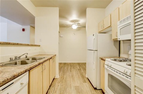 A kitchen with a stove, sink, and cabinets.