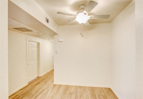 A room with a ceiling fan and wooden flooring.