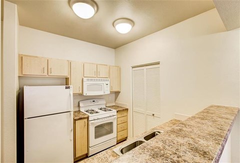 A kitchen with a white refrigerator, microwave, and oven.