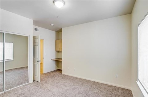 A room with a carpeted floor and a window on the right side.