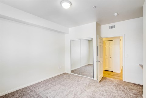 A room with a carpeted floor and a door leading to another room.