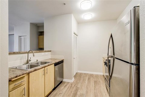 A kitchen with a refrigerator, sink, and cabinets.