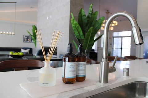 A kitchen counter with a sink, a diffuser, and two bottles of diffuser oil.