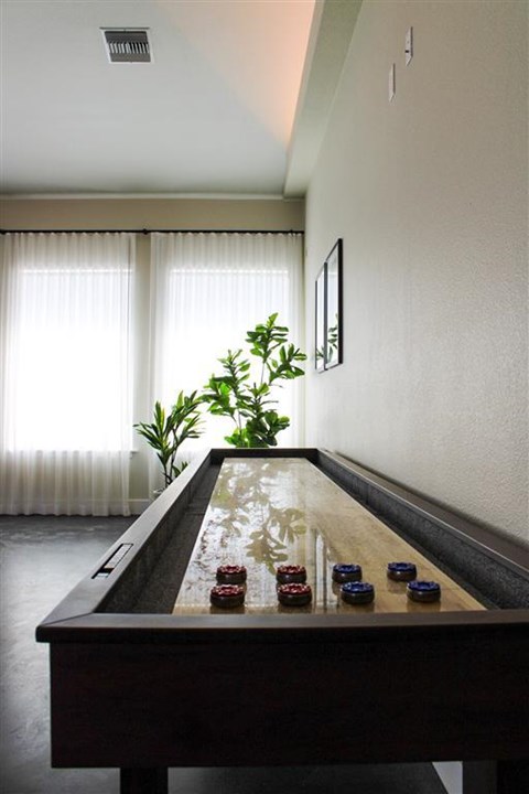 A pool table with red balls is in the middle of a room with a plant and picture on the wall.
