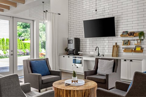 A modern living room with grey chairs and a white brick wall.
