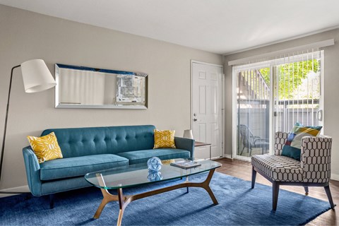 A living room with a blue couch and a glass coffee table.