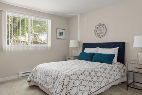 A bedroom with a large bed and a window with blinds.