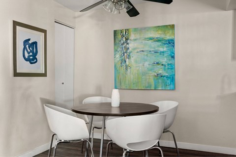 A painting hangs on the wall above a table with chairs.