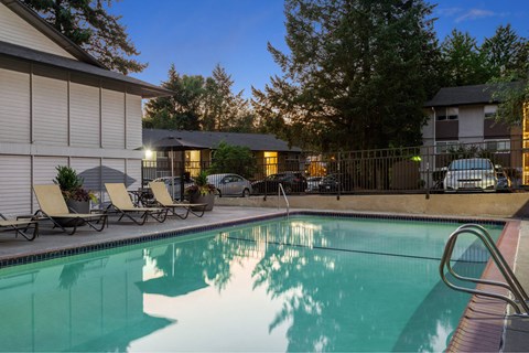 A pool with a metal ladder and a few chairs.