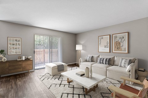 A living room with a white couch, a wooden chair, a coffee table, and pictures on the wall.