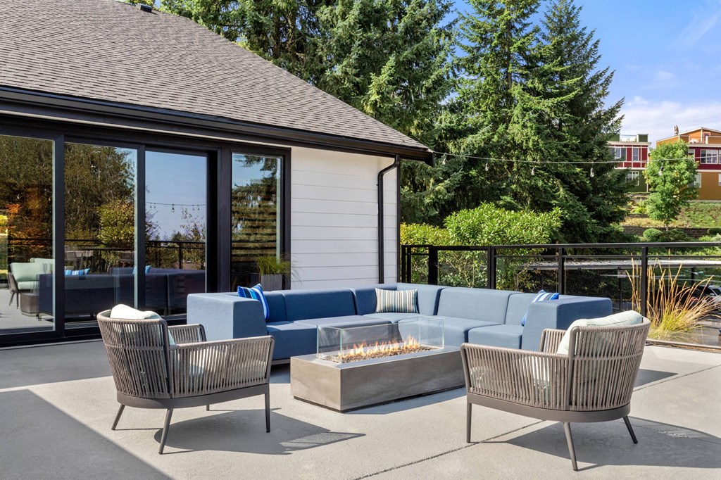 A patio with a fire pit and chairs.
