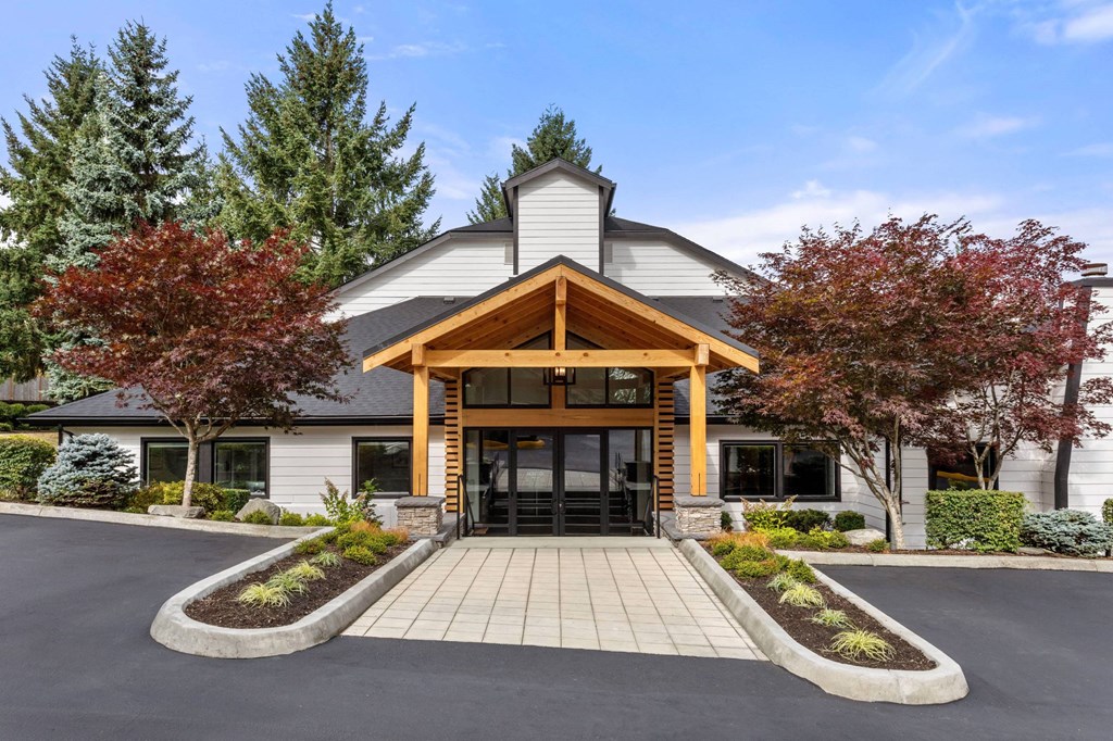 A modern building with a wooden front entrance and a landscaped area in front.