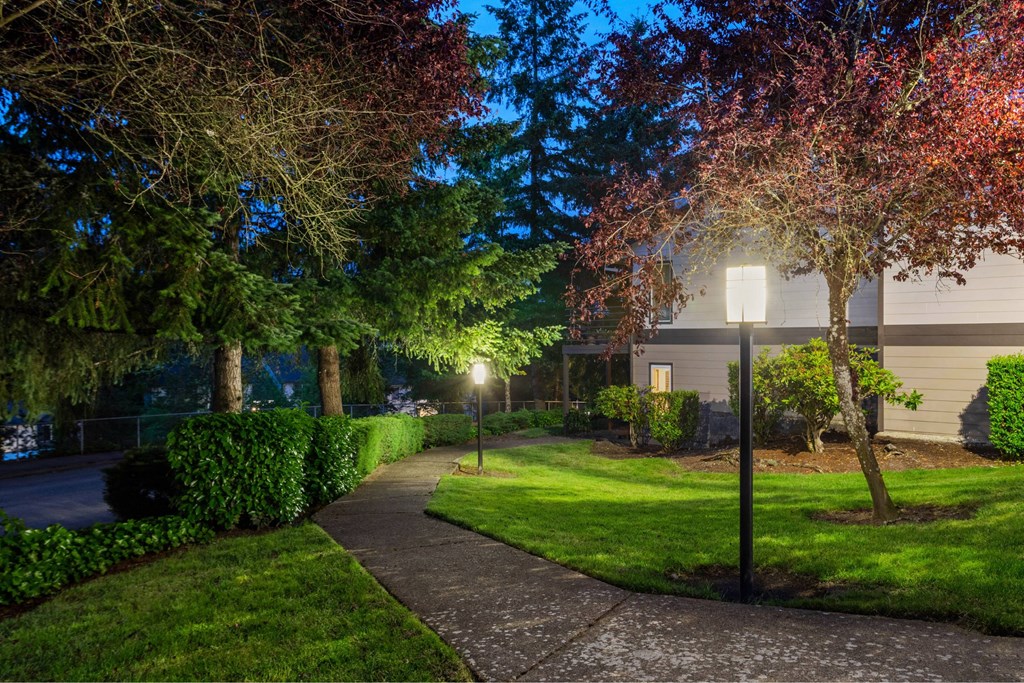 A tree with red leaves is in front of a house.