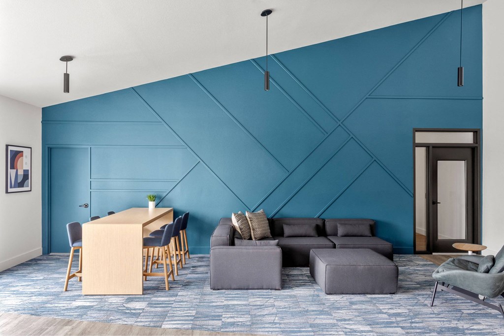 A blue wall with a white ceiling and a grey couch.