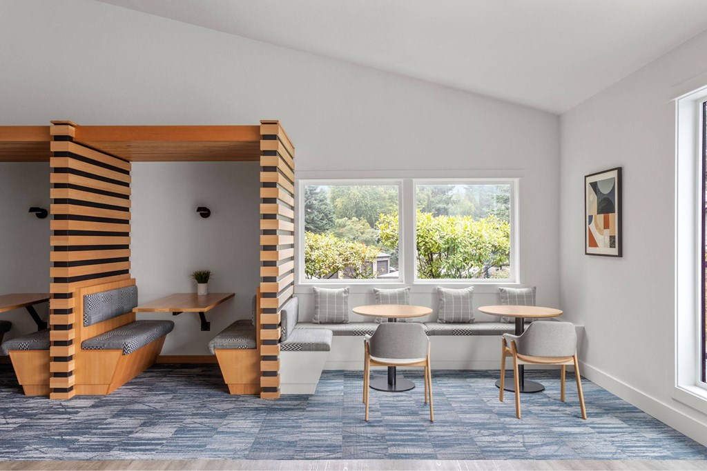 A room with a table and chairs and a window with a view of trees.