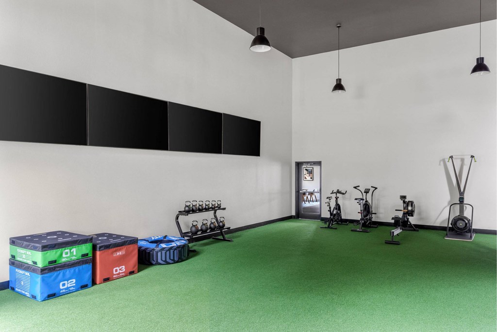 A gym with green floor and exercise equipment.