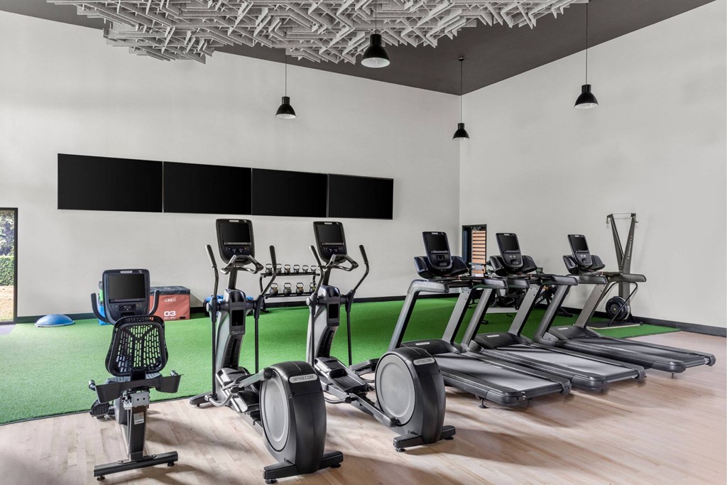 A gym with a row of treadmills and elliptical machines.