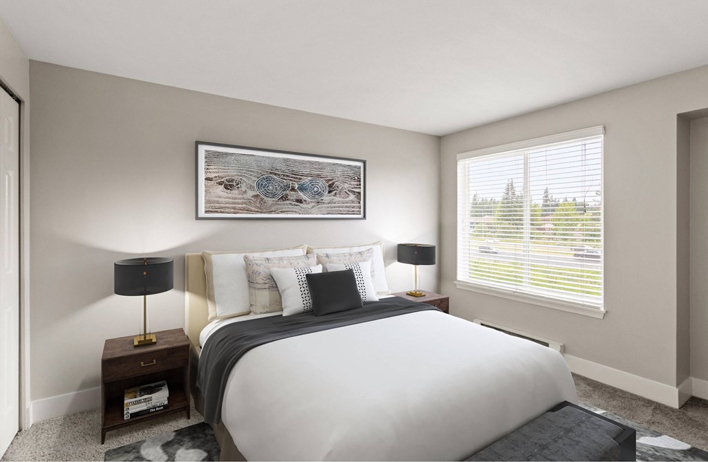 A bedroom with a large bed, a nightstand with a lamp, and a framed picture on the wall.