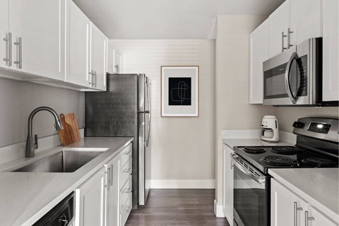 A kitchen with white cabinets and a black refrigerator.