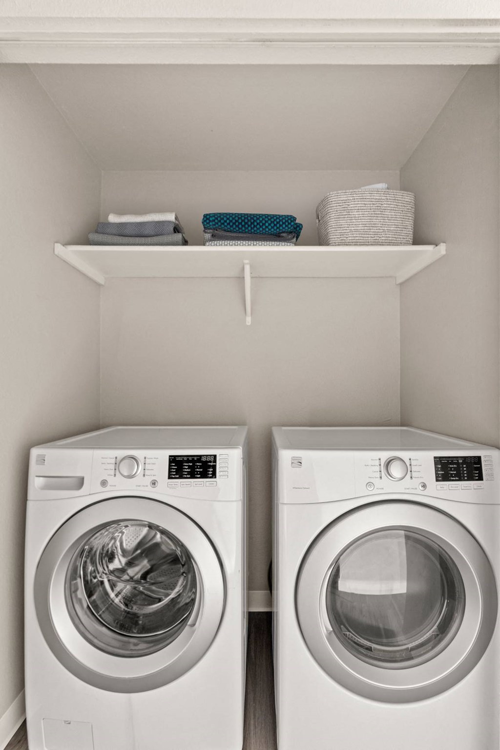 Two white front loading washing machines in a laundry room.