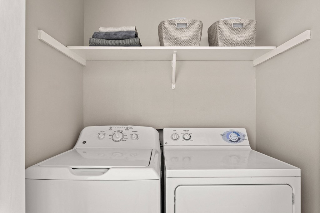 Two white washing machines in a laundry room.
