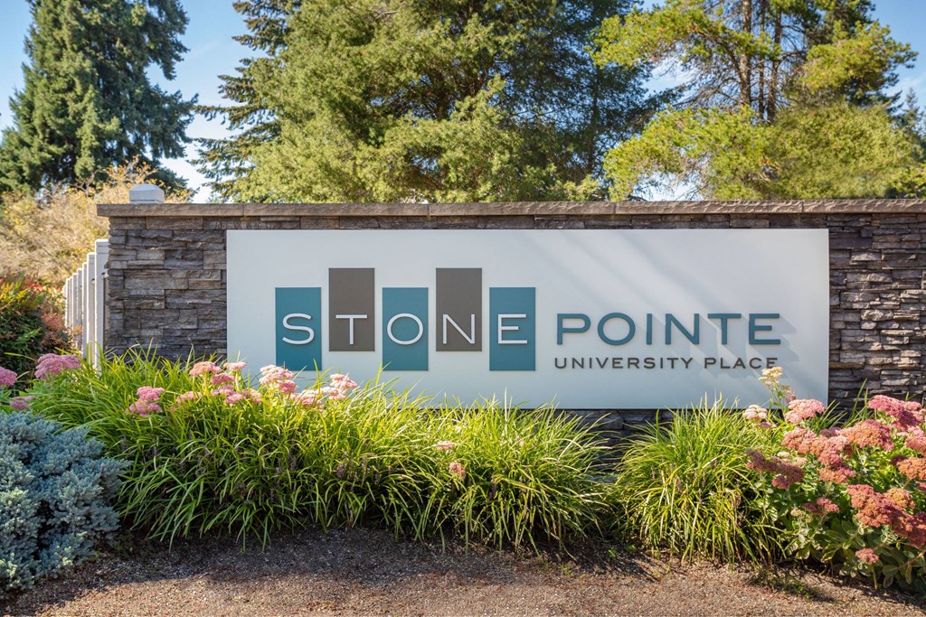 A sign for Stone Pointe University Place surrounded by flowers.