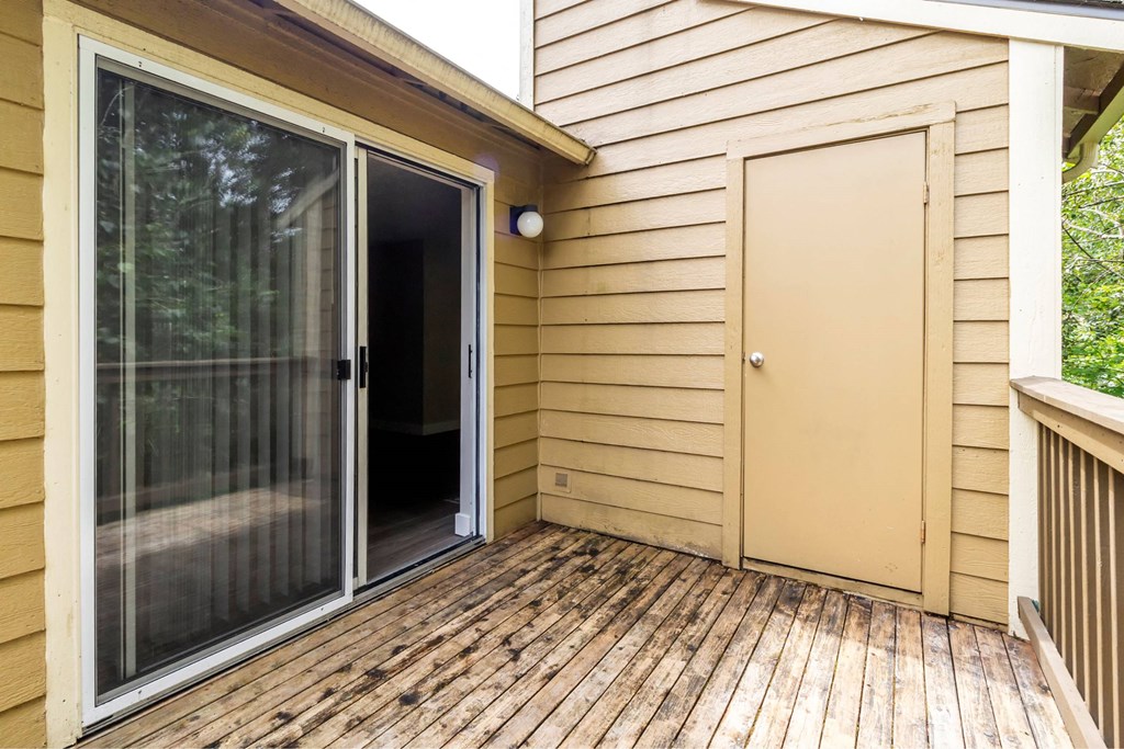 A wooden deck with a sliding glass door and a brown door.