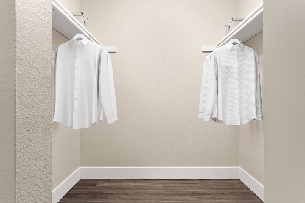 Two white shirts hanging on a wall.
