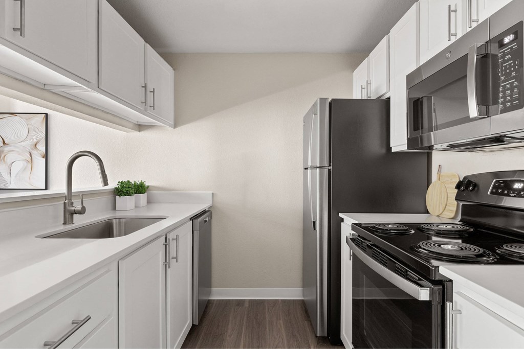 A kitchen with white cabinets and a black refrigerator.