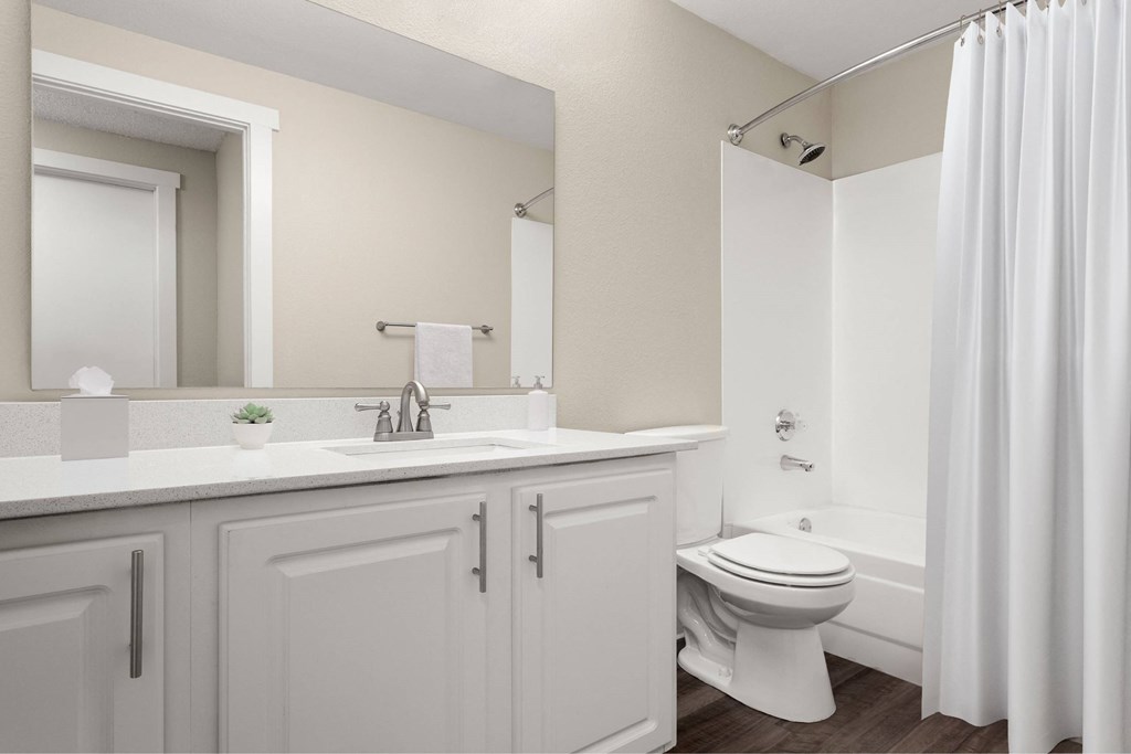 A white bathroom with a toilet, sink, and mirror.