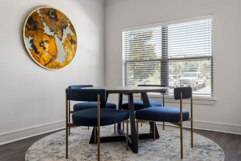 A round artwork hangs on a wall above a table with chairs.